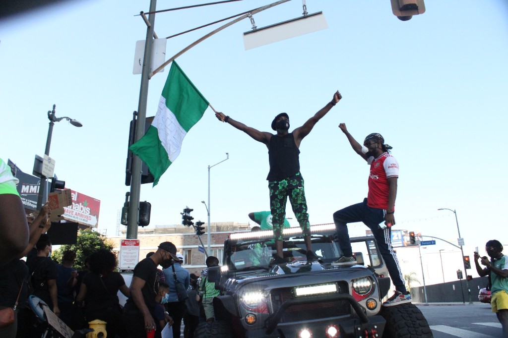 Demonstrators stand atop a vehicle and wave the Nigerian flag during an End SARS protest in Los Angeles.
